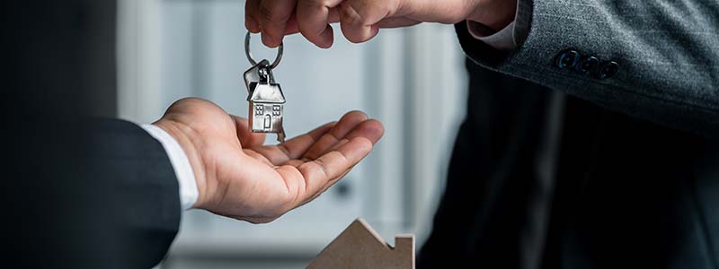 Buisness man holding a commercial building in one hand and a home in the other